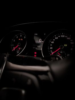 Detailed close-up of car speedometer and tachometer with illuminated indicators.