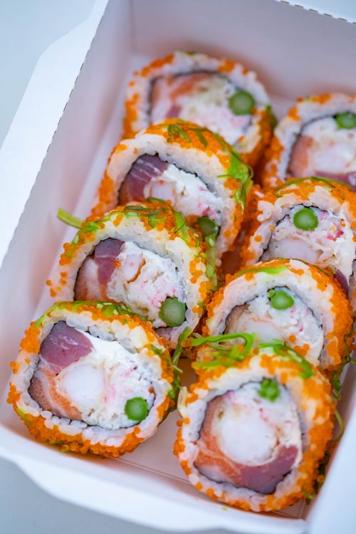 Free Vibrant sushi rolls in a white takeout box featuring roe, asparagus, and salmon. Stock Photo