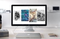 现代办公桌配备了时尚的电脑显示器，屏幕上显示着抽象艺术品