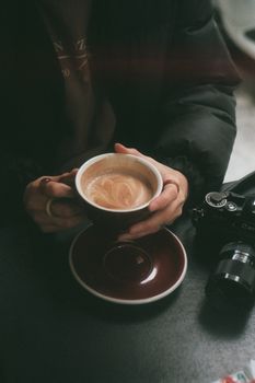 Warm coffee cup held by hands next to a vintage camera in an Istanbul café.