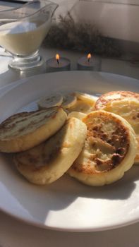Cozy breakfast with syrniki and candles, perfect for a warm morning meal.