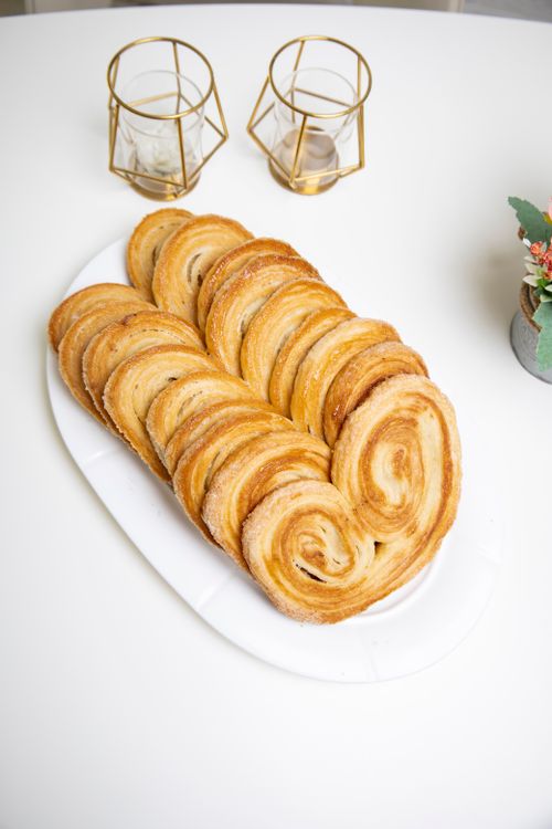 Free Freshly baked spiral pastries on a white plate with gold candle holders in the background. Stock Photo