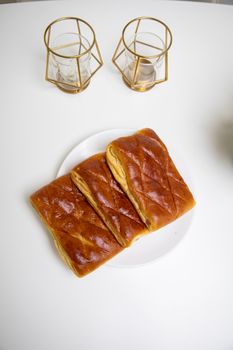 Three pieces of freshly baked bread on a white plate with elegant gold candle holders.