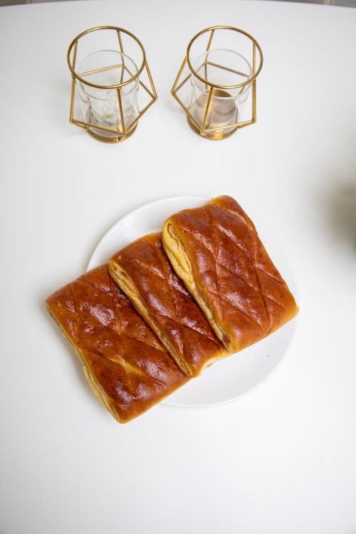 Free Three pieces of freshly baked bread on a white plate with elegant gold candle holders. Stock Photo