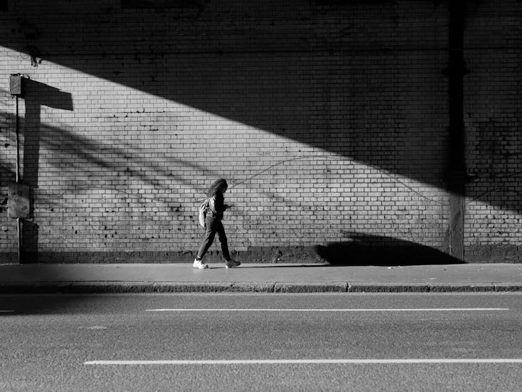 Woman Walking On Sidewalk In Tunnel