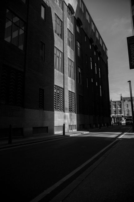 A striking black and white photograph of a modern urban street with architectural shadows.
