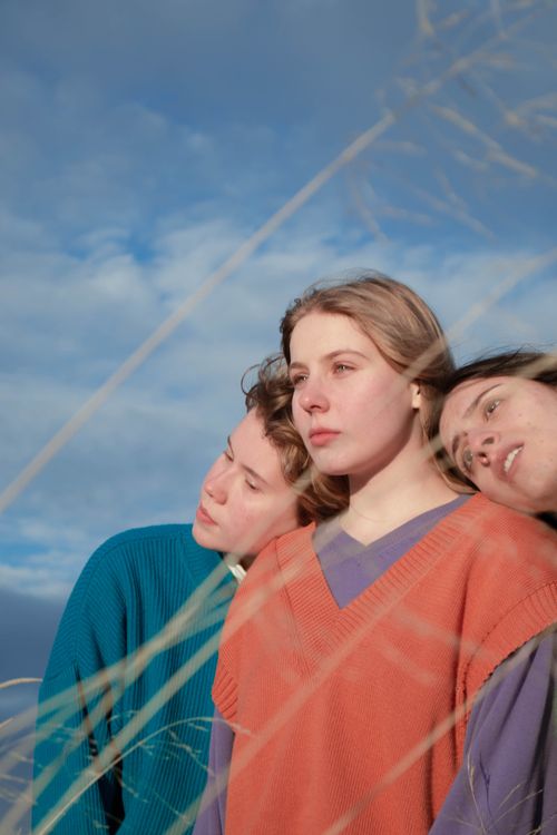 Free Three individuals enjoying peaceful moments under a cloudy sky amid natural scenery. Stock Photo