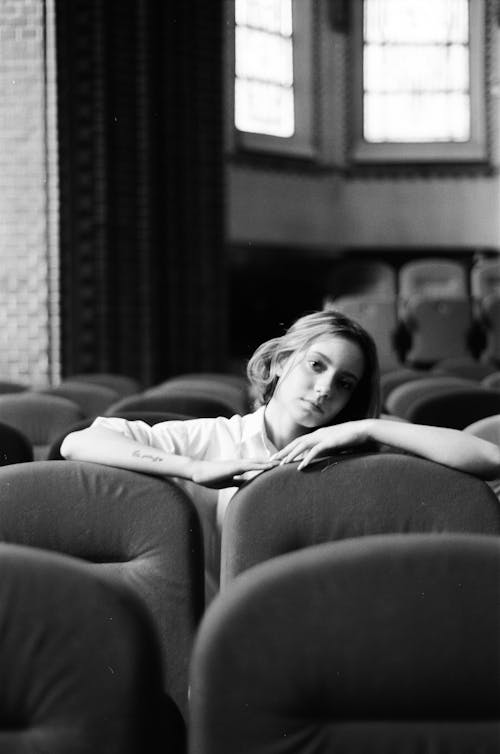 Grayscale Photo of Woman in White Shirt Sitting on Sofa