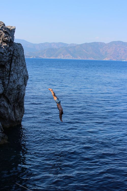 Free A man dives off a cliff into the sea in Marmaris, Türkiye, showcasing adventure and thrill. Stock Photo