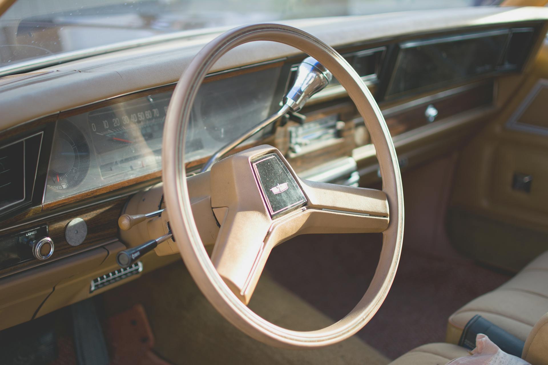 Explore the detailed view of a vintage car's interior featuring a wooden dashboard and classic steering wheel.