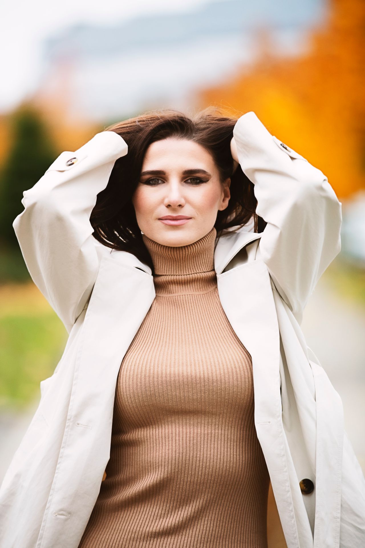 Woman in a brown turtleneck dress and white trench coat