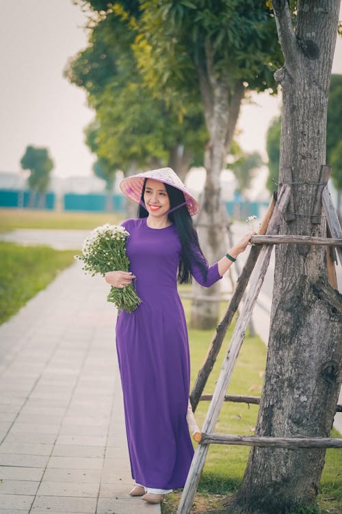 Free Woman in Purple Long Sleeve Dress Holding Bouquet of Flowers Stock Photo