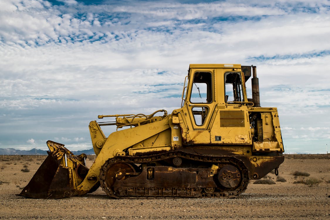 Free Yellow Heavy Equipment on Brown Field Under White Clouds and Blue Sky Stock Photo