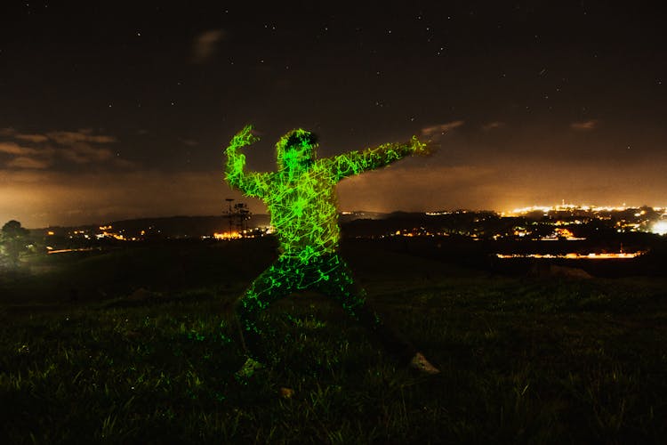 Man In Green Lights Dancing In Field At Night