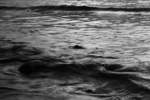 Free Black and white photo of ocean waves gently flowing over rocks with a tranquil atmosphere. Stock Photo