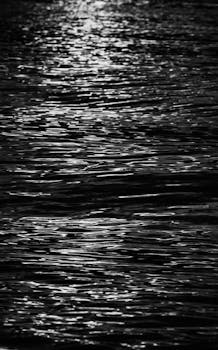 A captivating black and white image of ocean waves reflecting moonlight, creating a serene and tranquil atmosphere.