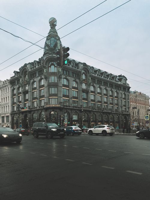 Free Singer House at an intersection in Saint Petersburg, Russia with moving vehicles on a cloudy day. Stock Photo