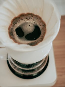 Top view of freshly brewed coffee cascading through a filter, capturing rich aroma and texture.