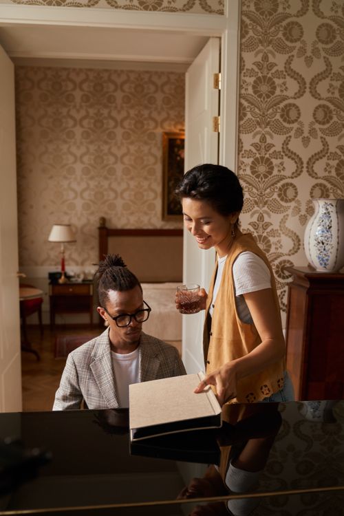 Free A man and woman are collaborating at a piano in an elegant room, blending creativity and style. Stock Photo