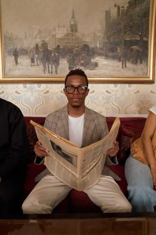 Free Stylish man with glasses reads a newspaper in a classic room with vintage painting. Stock Photo