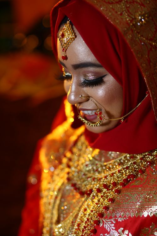 Free A South Asian bride adorned in vibrant red traditional wear with intricate gold jewelry, exuding elegance. Stock Photo
