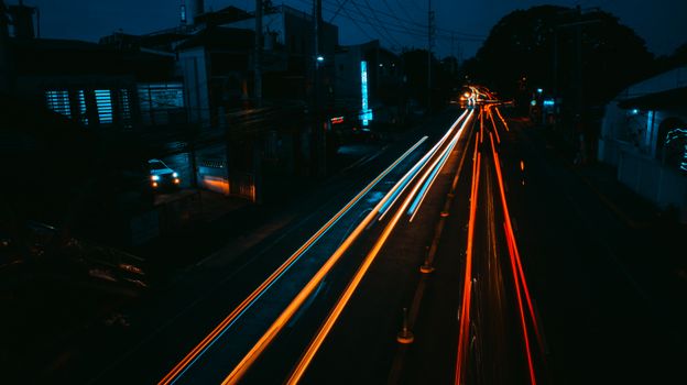 Dynamic long exposure photography capturing busy city streets with vibrant light trails at night.