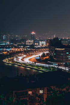 Long exposure night view of İzmir cityscape with light streaks and skyline reflections.