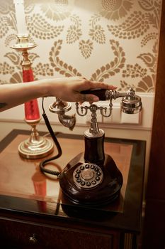 Close-up of a vintage rotary phone with a hand picking up the receiver in a luxurious home setting.
