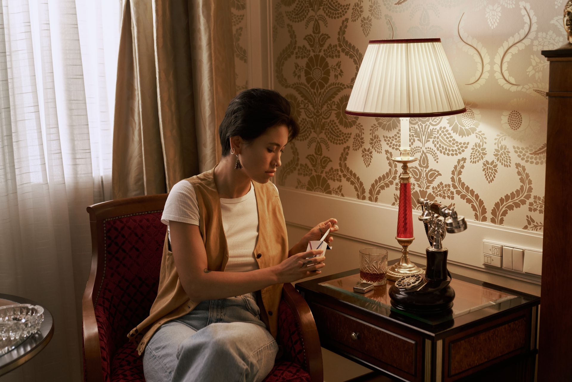 Woman in elegant setting, holding a small box, exuding luxury and retro style. Warm lighting.
