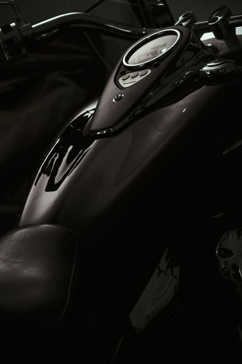 Free Dark close-up of a motorcycle gas tank with a focus on the handle bar and dashboard. Stock Photo