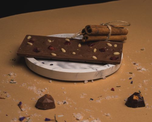 Free Delicious chocolate bar with nuts and berries on a marble plate, garnished with cinnamon sticks. Stock Photo