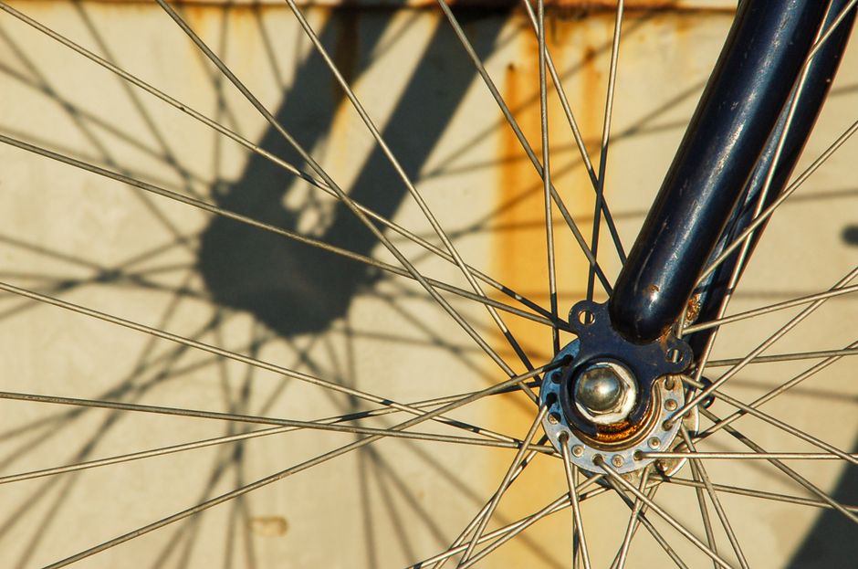 錆びた金属のスポークと影の演出を特徴とするヴィンテージ自転車ホイールの詳細なショット。