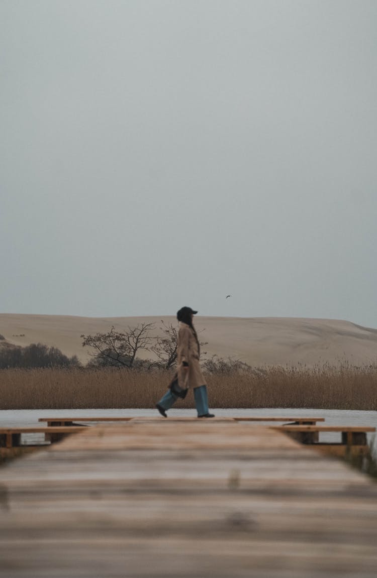 Woman Walking On Jetty On Lakeshore