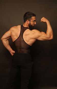 A muscular man flexing his biceps during a fitness photoshoot, showcasing strength and physique.