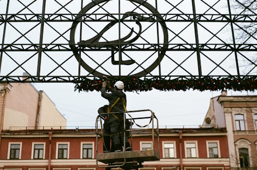 Man Wearing Safety Harness and Helmet Decorating a Metal Frame