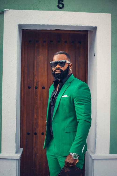 Free A Man in Green Suit Standing in Front of a Wooden Door Stock Photo