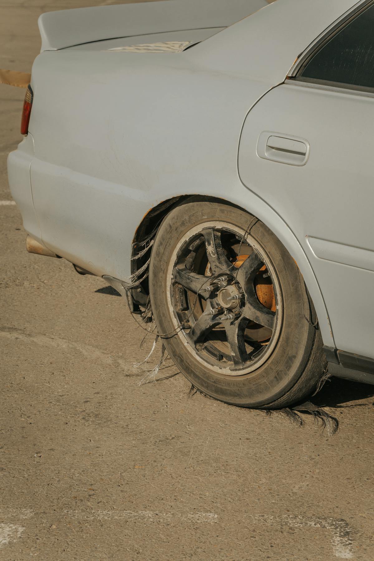 Severely damaged tire with blown-out sidewall showing catastrophic failure from road impact