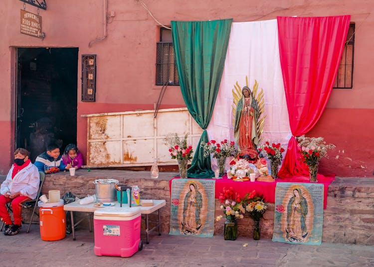 Family Celebrating Day Of The Dead Festival With Guadalupe Shrine Outside The House