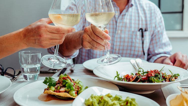 Two Unrecognizable People Holding Glasses Of White Wine At Vegan Lunch