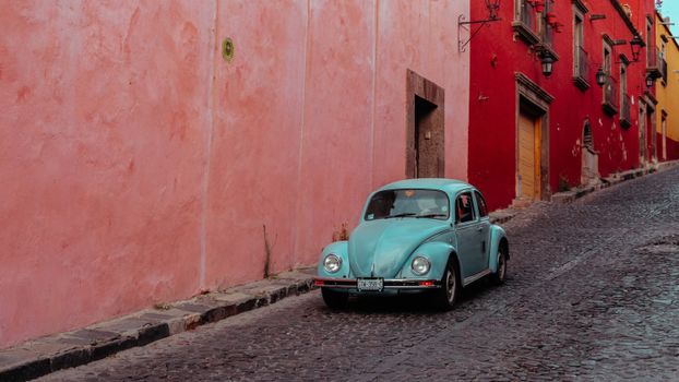 Turquoise Buggy Moving Along Street with Pink and Red Buildings