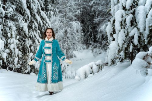 Free Woman in blue coat standing in a snowy forest, depicting a serene winter scene. Stock Photo