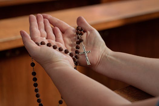 Close-up of hands holding rosary beads in prayer at a church in Warsaw, Poland.
