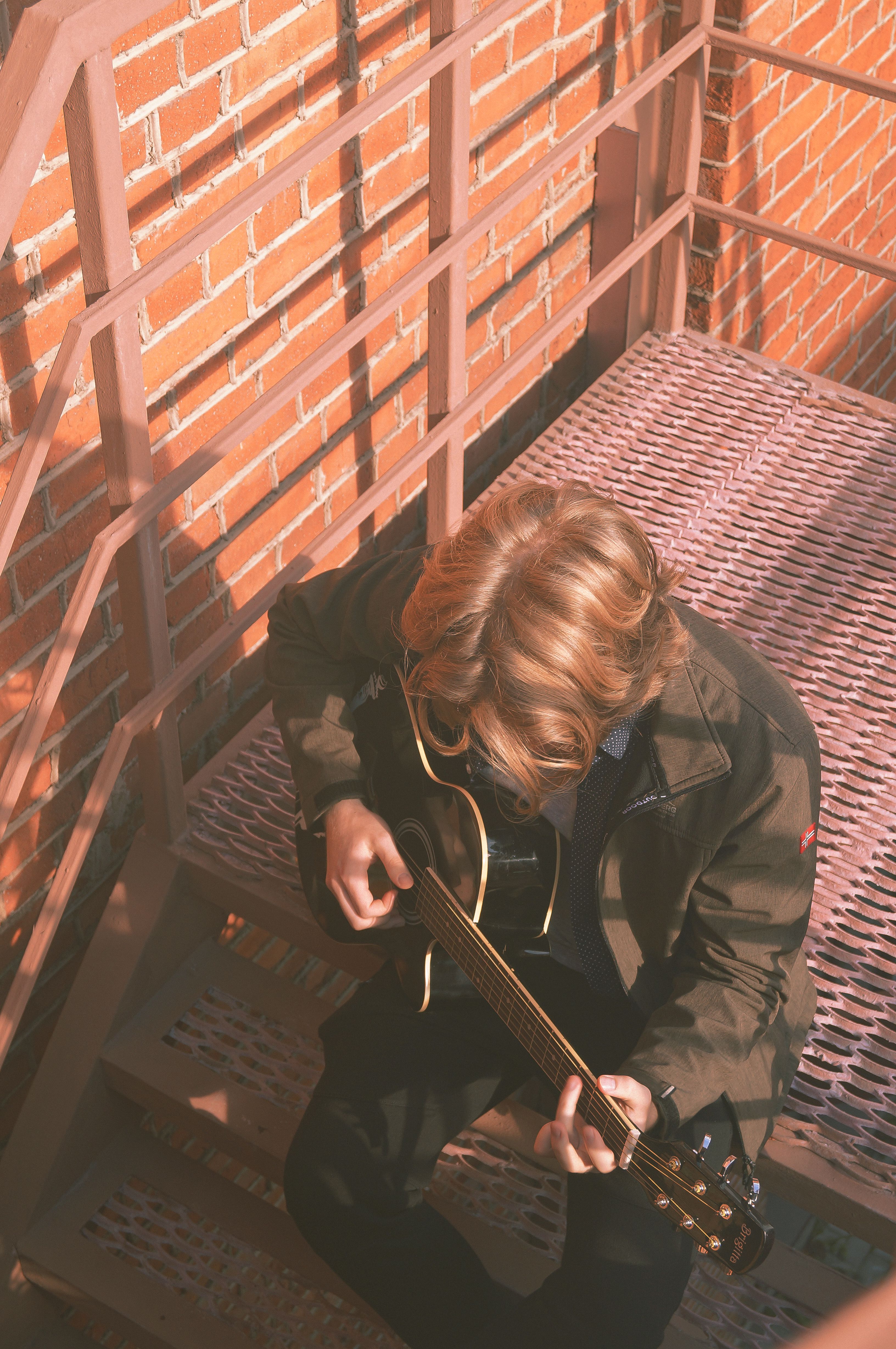 A Person Playing Guitar Sitting on the Stairs · Free Stock Photo