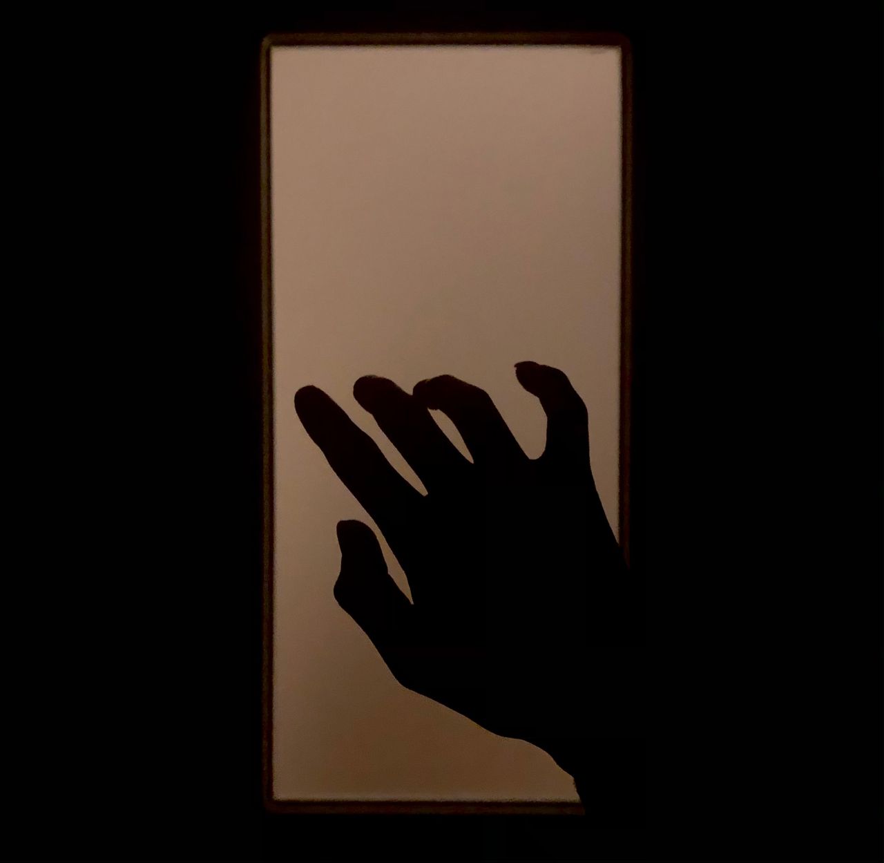 a dramatic silhouette of a hand reaching towards light evoking mystery