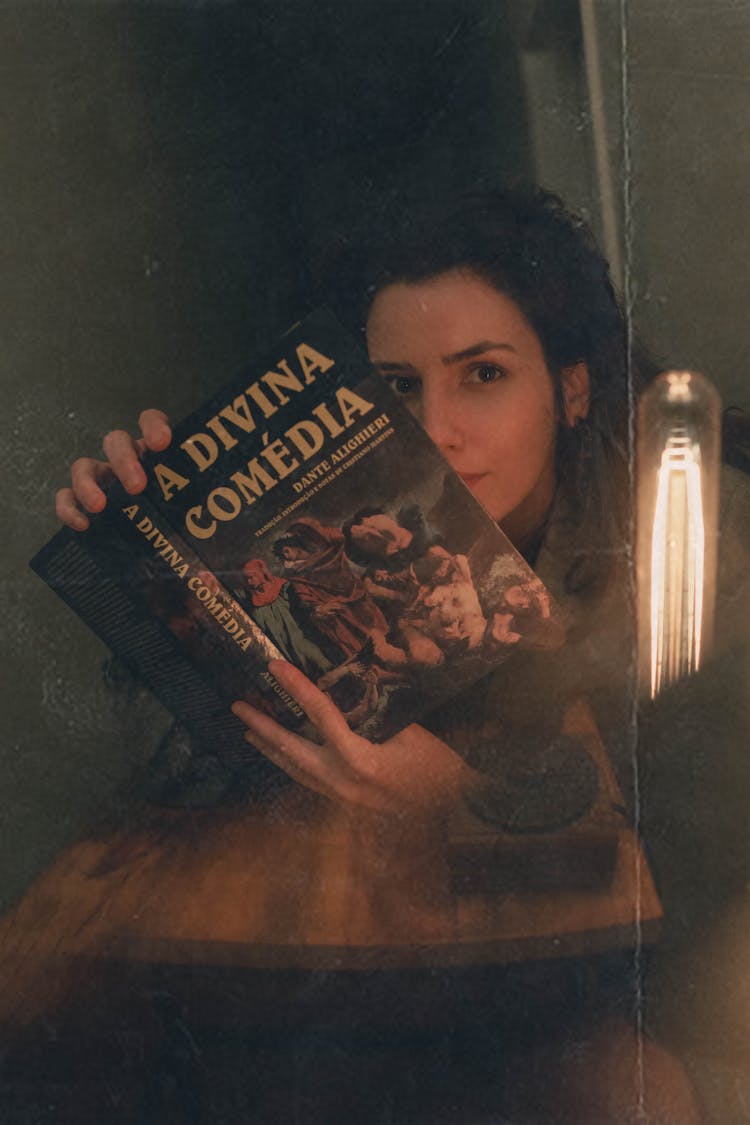 An Old Photo Of A Woman Holding The Divine Comedy Book