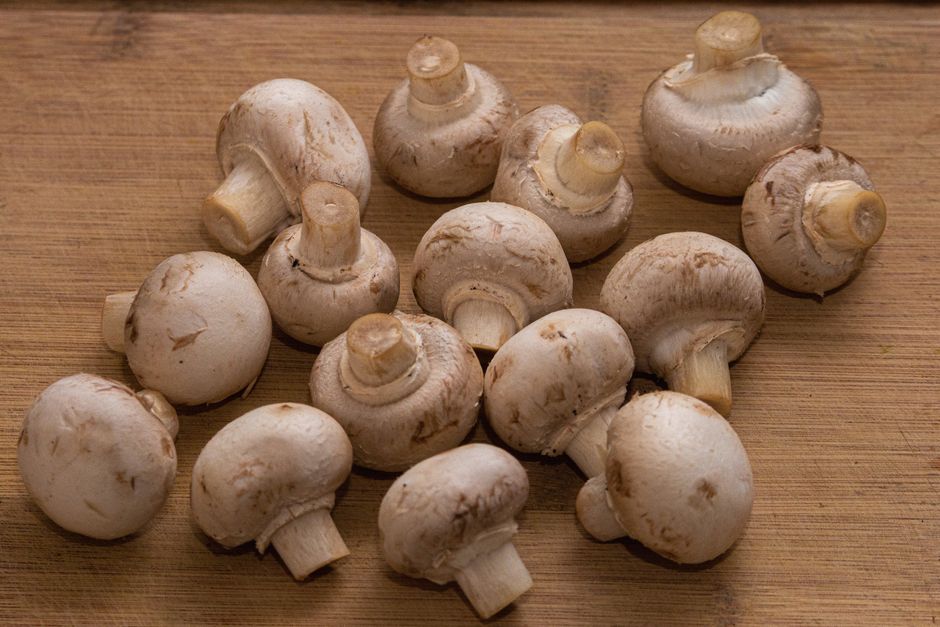 Close-up of fresh white mushrooms on a wooden cutting board, perfect for culinary projects.