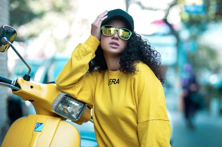 Woman In Sunglasses And Yellow Hoodie Leaning On Scooter