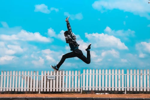 Free Man Jumping over White Fence Stock Photo