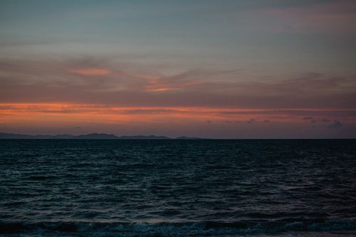 Free Peaceful ocean scene at sunset with a vivid horizon and gentle waves. Stock Photo