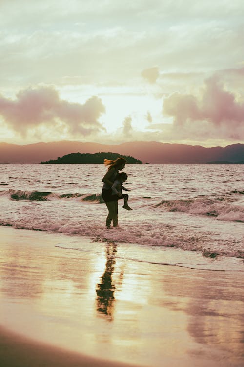 Photo of a Mother Carrying Her Child on a Beach